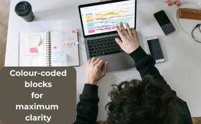 Overhead view of a laptop displaying a color-coded Daily Schedule With Timers next to a physical notebook.