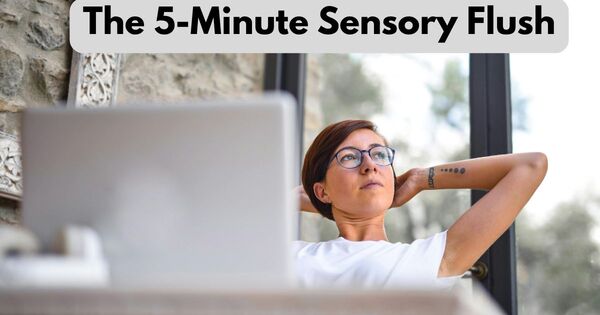 Writer in glasses stretches by window taking a sensory flush break from a laptop.